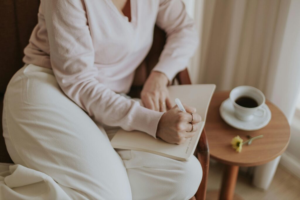 A person journaling in a cozy room with a cup of coffee. Warm and inviting atmosphere.